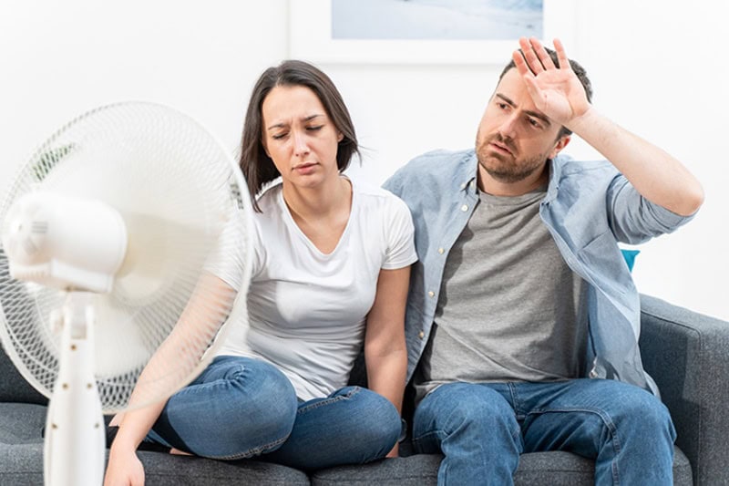 3 Tips to Prevent AC Breakdown During a Heat Wave. Couple trying to refresh during summer heat wave.