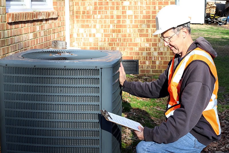 5 Reasons Why Regular HVAC Maintenance is Essential for Meigs County Homeowners. Home inspection of central air unit by a maintenance worker.